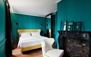 Quarto com cama, poltrona, cômoda e luminárias na parede.