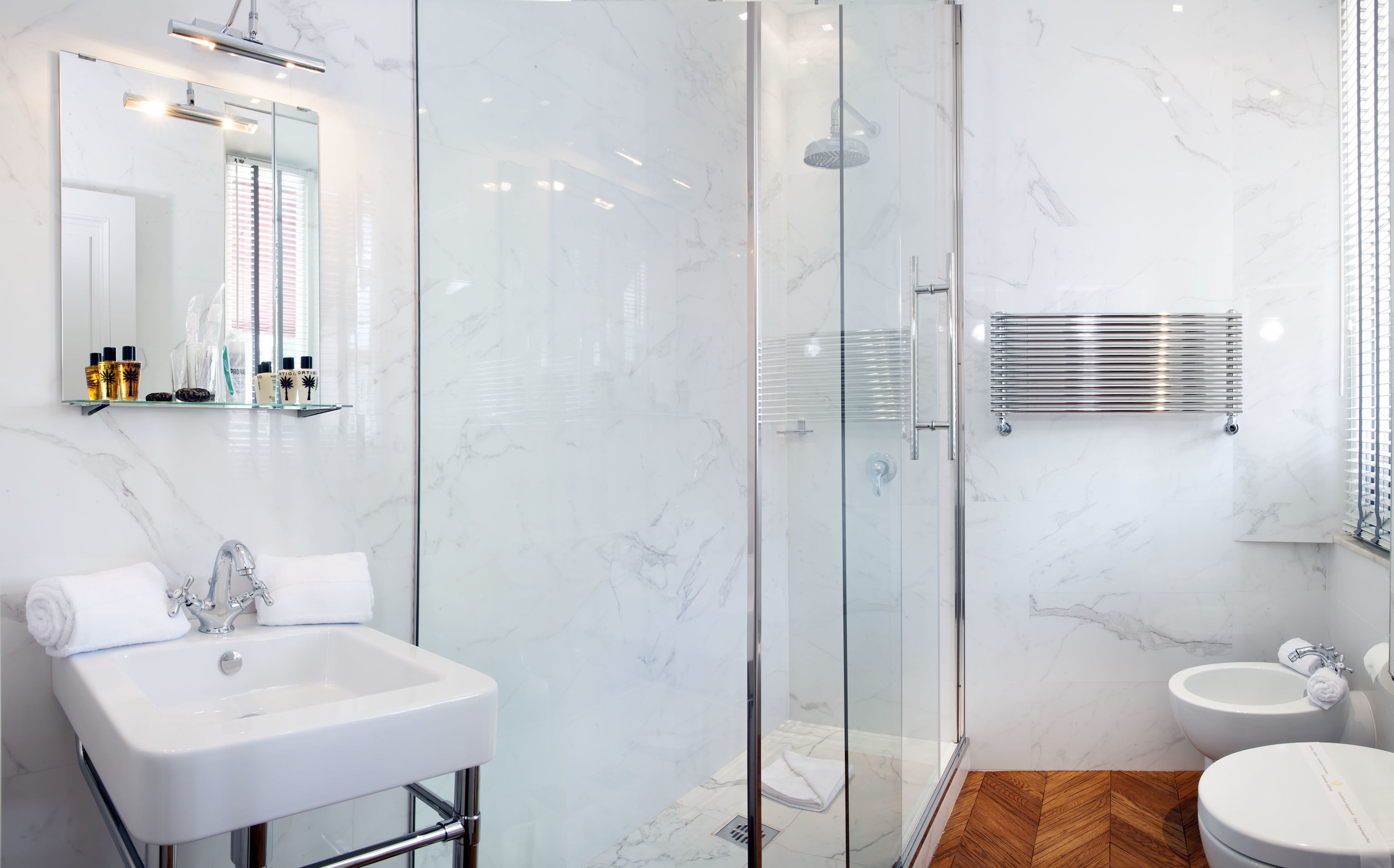 A modern bathroom with a glass-enclosed shower, a white sink, and a toilet.