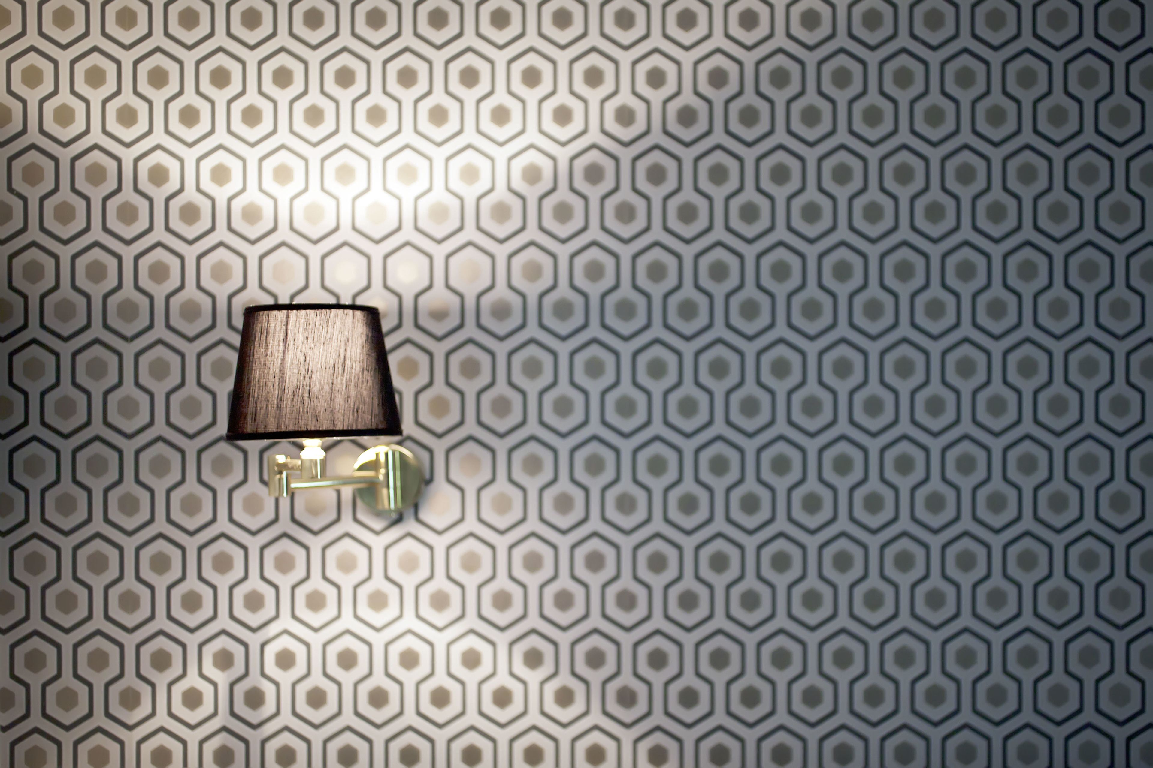 Parede com padrão hexagonal e luminária de parede.