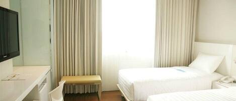 A hotel room with two beds, a desk, a chair, and a television.