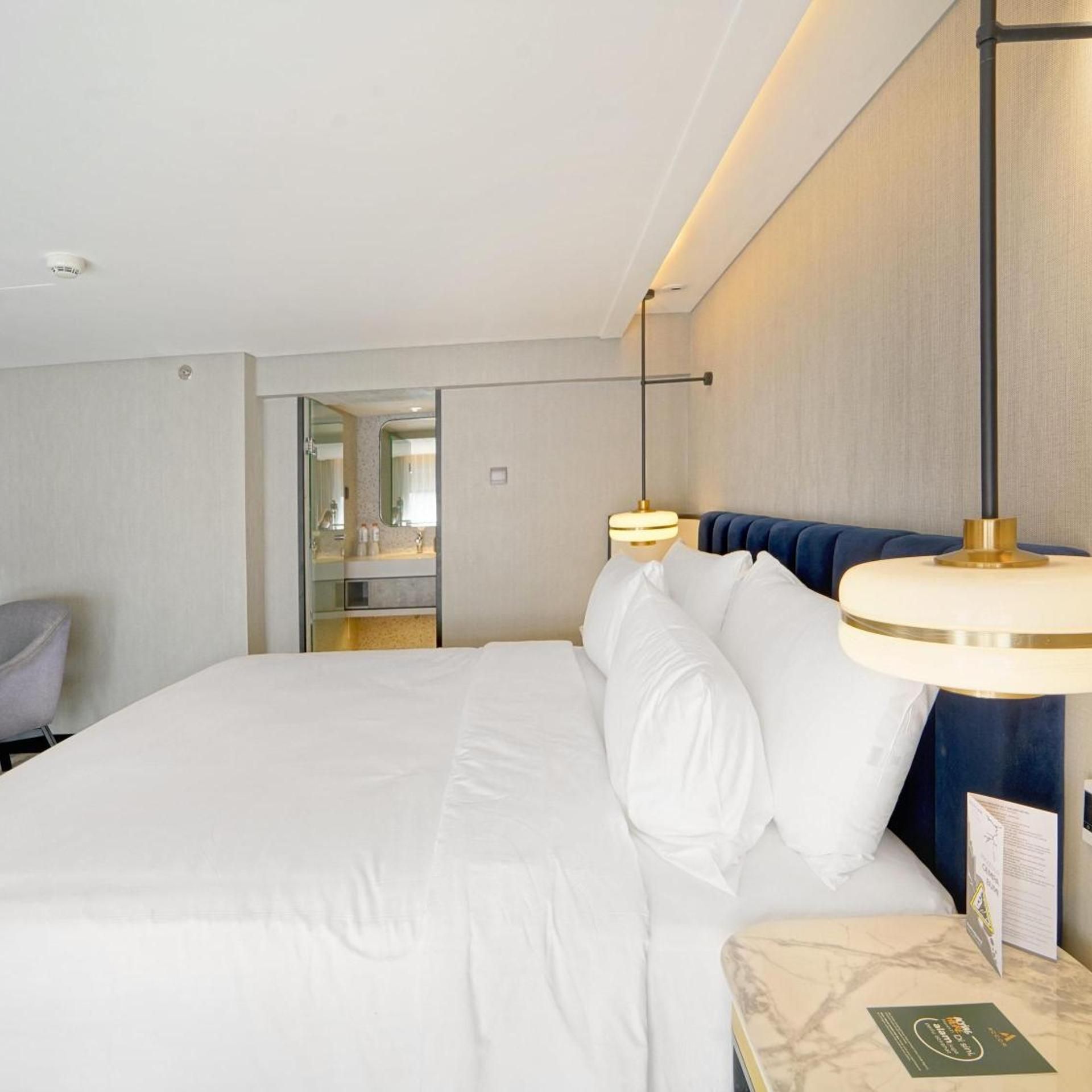 A hotel room with a large bed, bedside tables, a desk, and a mirror.