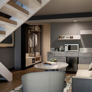 A modern apartment with a staircase, a kitchen with a microwave, and a seating area with a table. - Everbright (Surabaya)