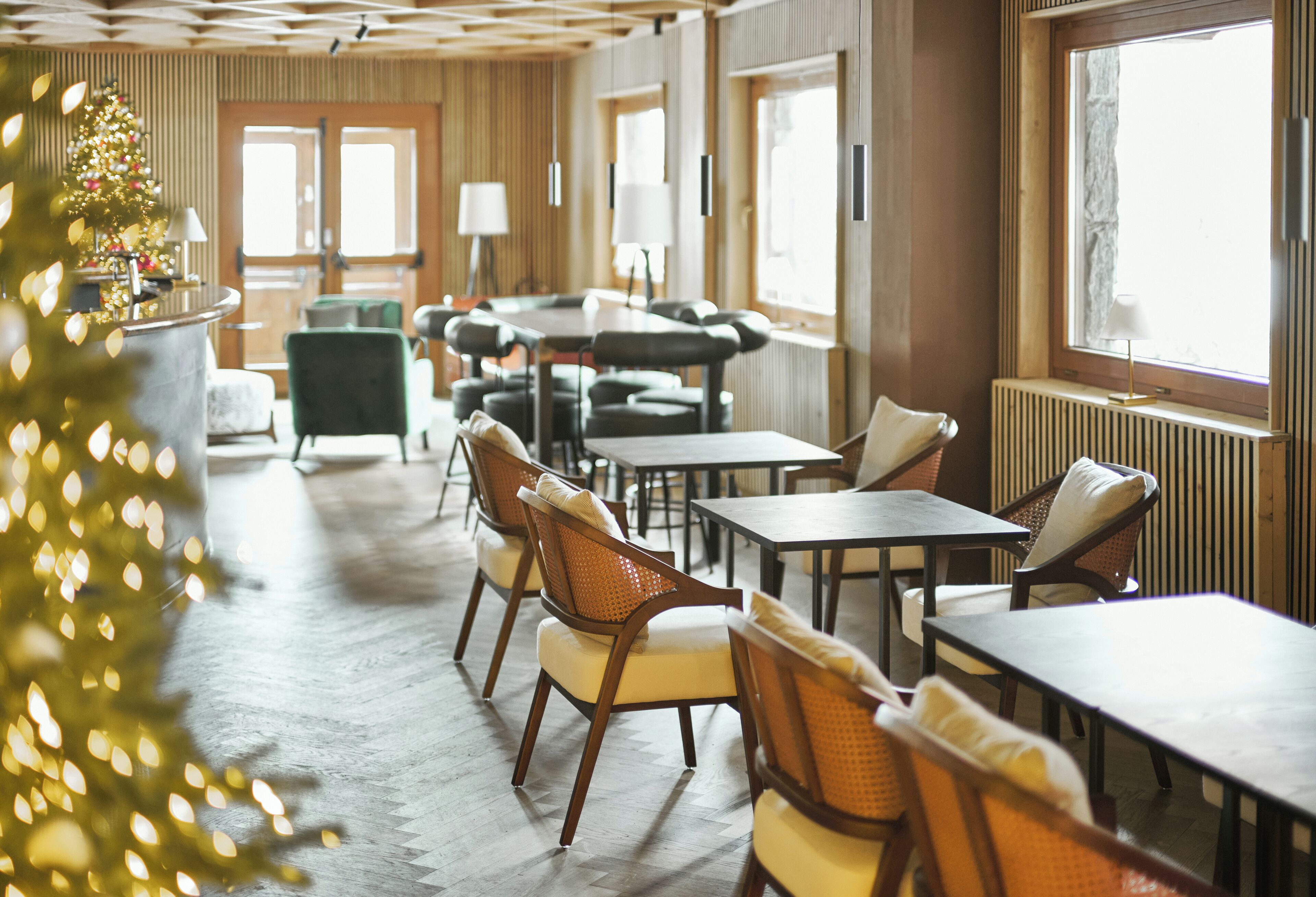 Un hall de hotel con paneles de madera, un árbol de Navidad y mobiliario moderno.