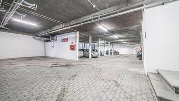 Un garaje de estacionamiento con múltiples espacios, pisos de concreto e iluminación colgante.
