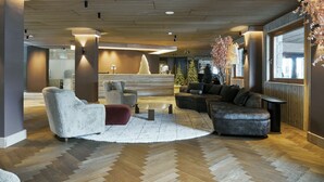 Un lobby moderno con techo de madera, asientos cómodos y un amplio ventanal con luz natural.