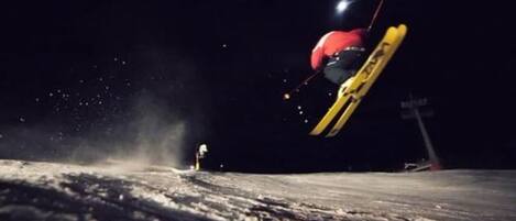 Un skieur en plein saut, au sommet d’une pente enneigée.
