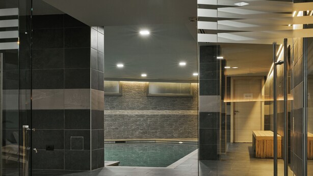 Un moderno vestíbulo de hotel con separador de vidrio, zona de piscina y cartel de habitación privada.