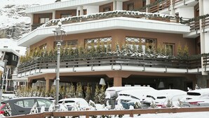 Un hotel con varios balcones, paisajes nevados y montañas al fondo.