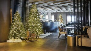 Un interior moderno con dos árboles de Navidad, un trineo de madera y una zona de bar.