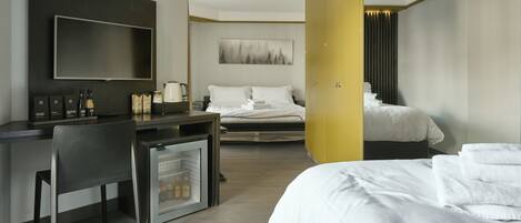 A hotel room with a bed, a desk with a chair, a television, and a small refrigerator.