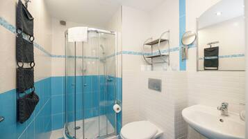 A bathroom with a glass-enclosed shower, a white toilet, and a sink.