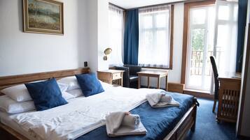 Habitación de hotel con una cama grande, un escritorio, una silla y vistas al exterior a través de las ventanas.