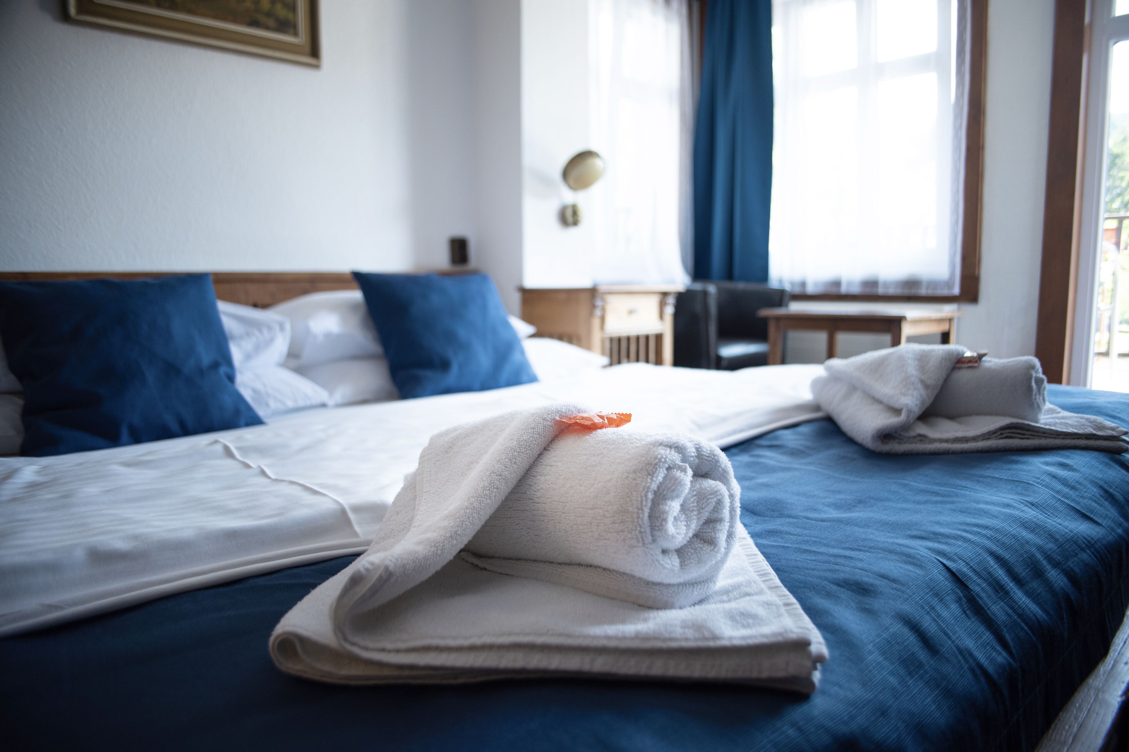 A hotel room with a neatly made bed, a small table, and a chair.