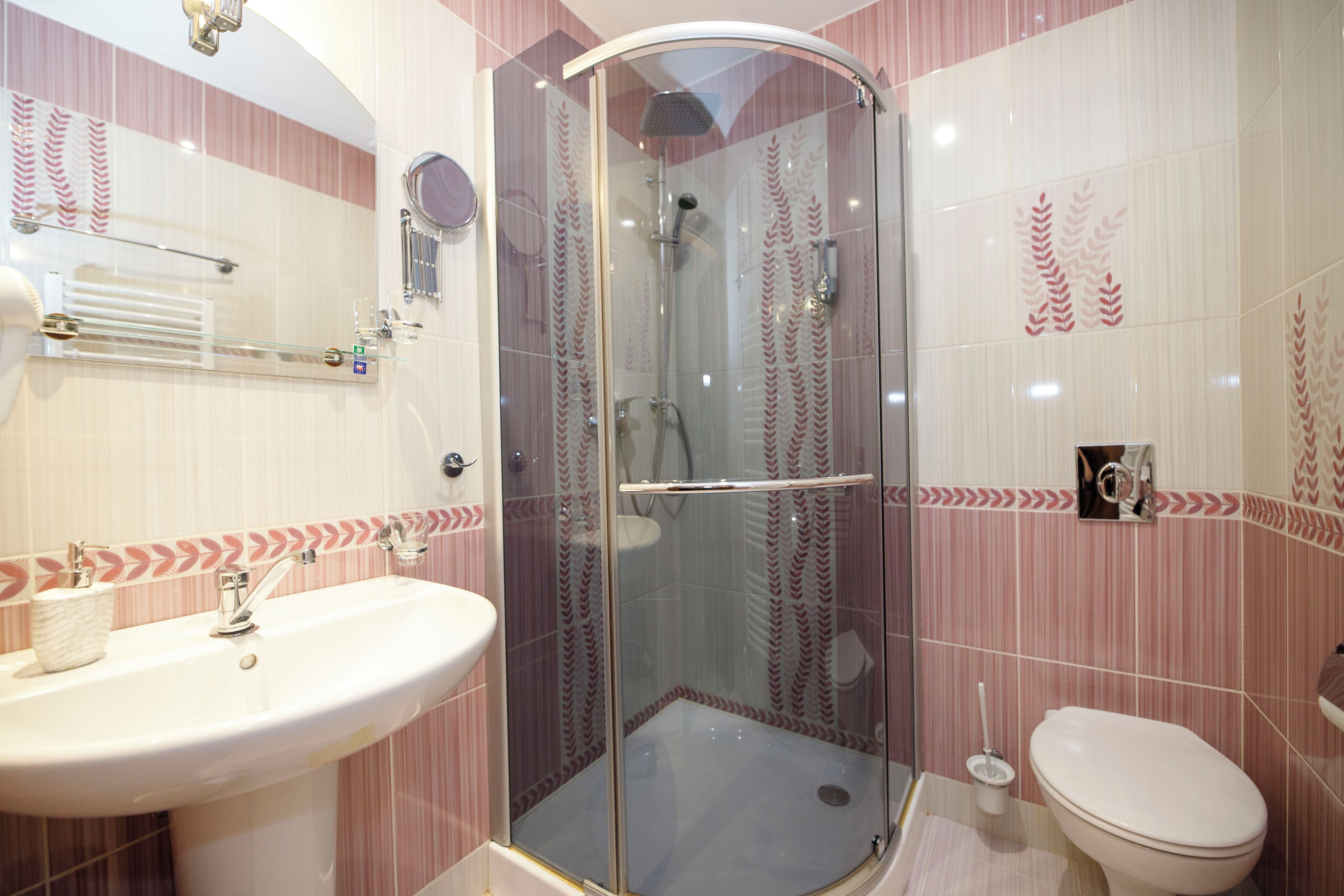 A bathroom with a glass-enclosed shower, a sink, and a toilet.