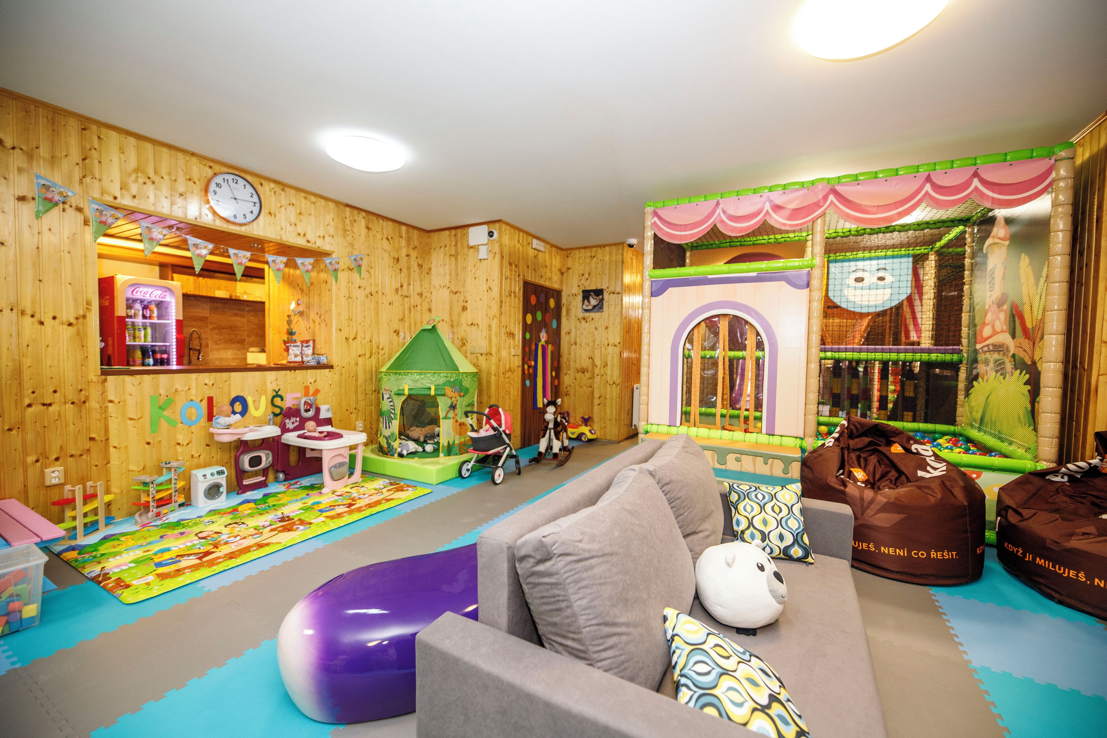 A children's playroom with a playhouse, toys, and a sofa.