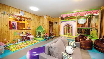 A children's playroom with a playhouse, toys, and a sofa.