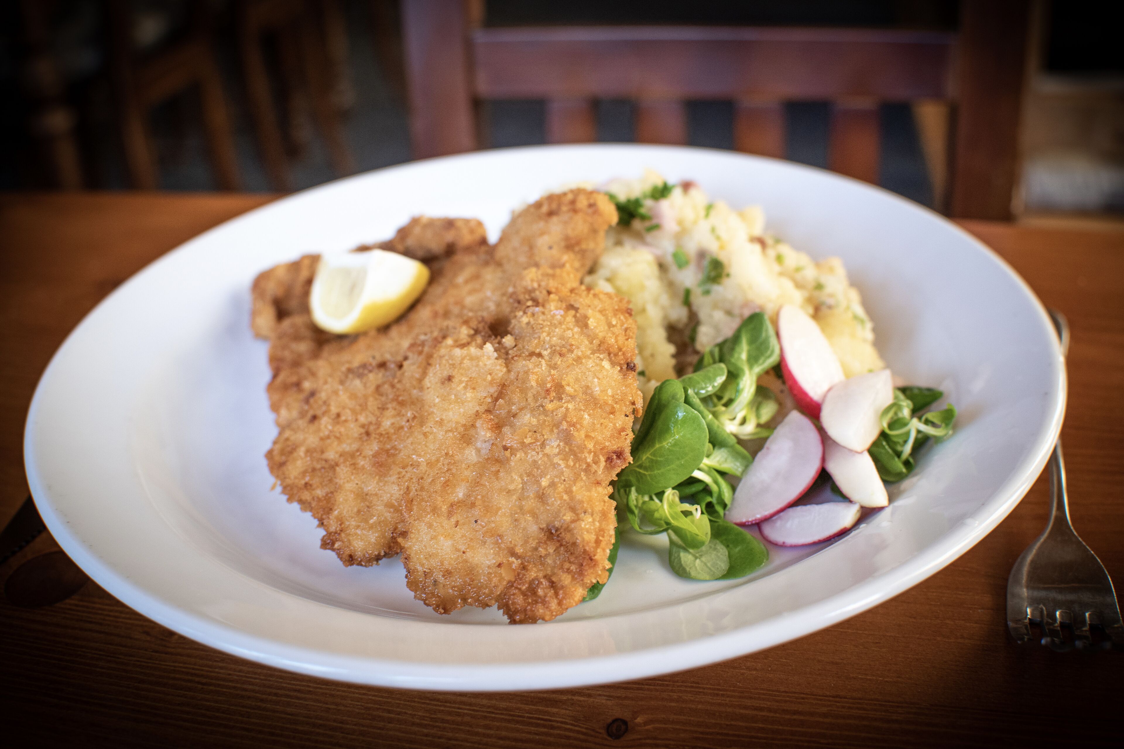 A plate with a breaded cutlet, mashed potatoes, and a side salad.