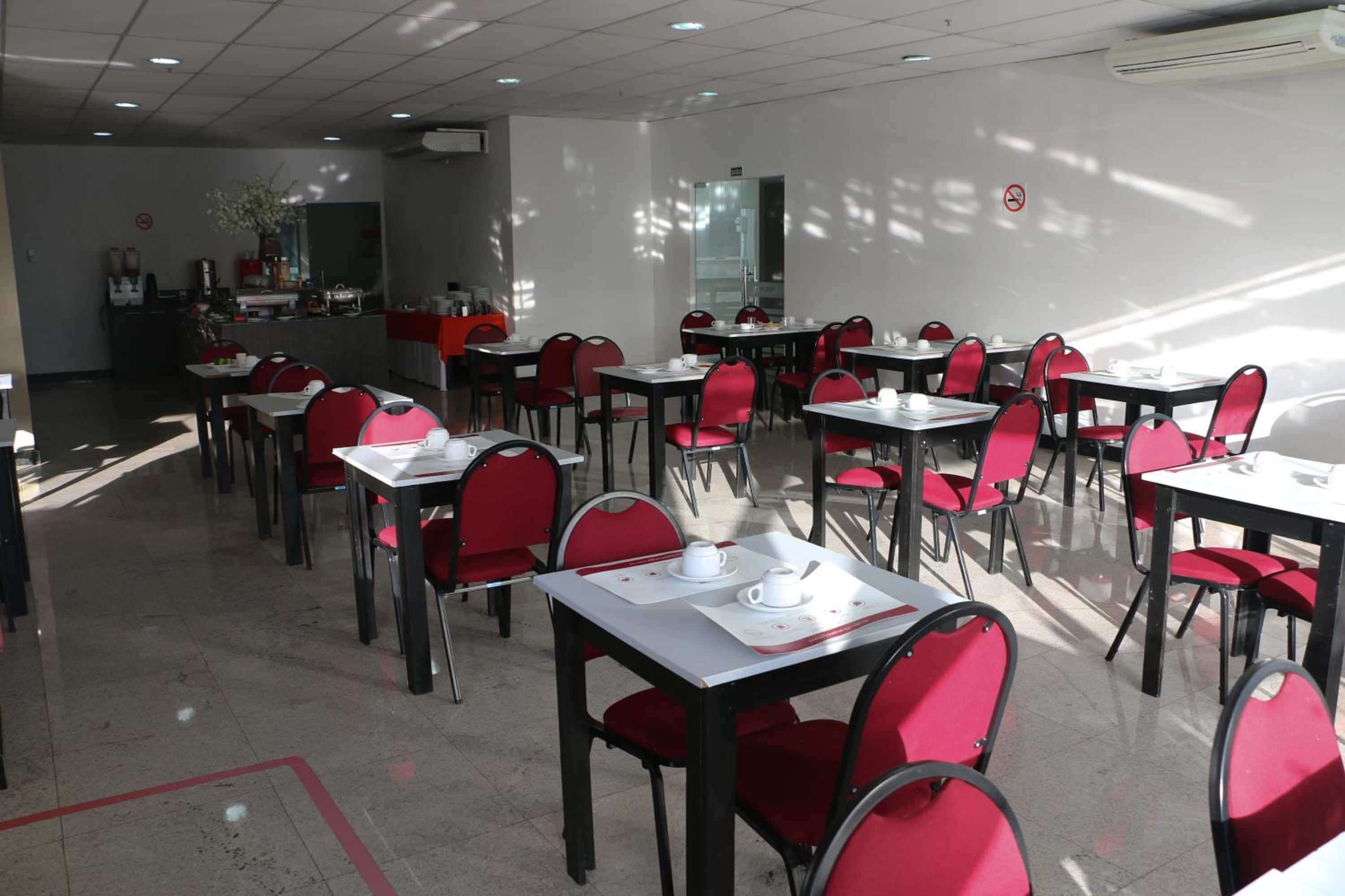 Un comedor con mesas y sillas, una zona de cocina y un separador de vidrio.