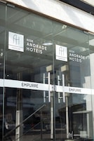 Entrada de un hotel con puertas de vidrio, identificada con las etiquetas "REDE ANDRADE HOTÉIS" y "EMPURRE".
