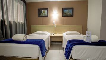 Una habitación de hotel con dos camas, una mesita de noche y una lámpara de pared.