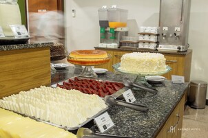 A buffet with various food items, including cakes and cheese.