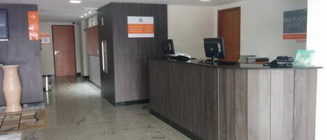A reception area with a wooden reception desk, a computer, and a sign indicating room rates.