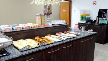 Mostrador de buffet con diversos alimentos y una máquina de café.