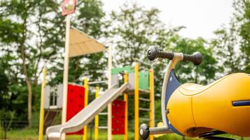 A playground with a yellow swing set and a slide.