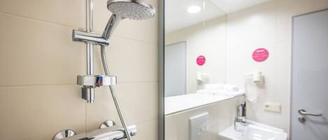 A modern bathroom with a chrome showerhead, a sink, and a mirror reflecting the room.