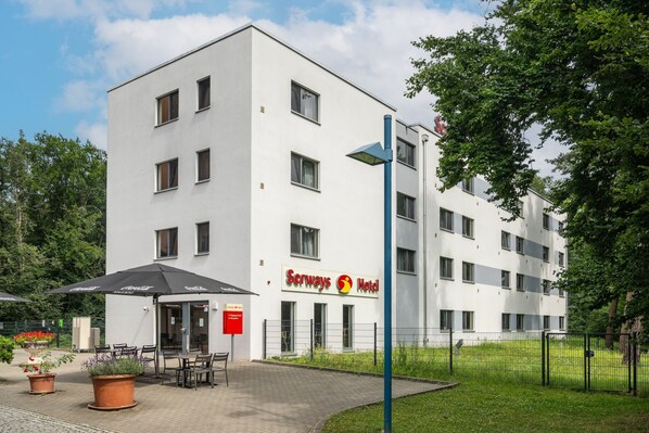 Un moderno edificio de hotel con fachada plana, múltiples ventanas y un letrero que dice "Serways Hotel".