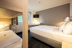 Una habitación de hotel con dos camas, un escritorio, un televisor y una ventana.