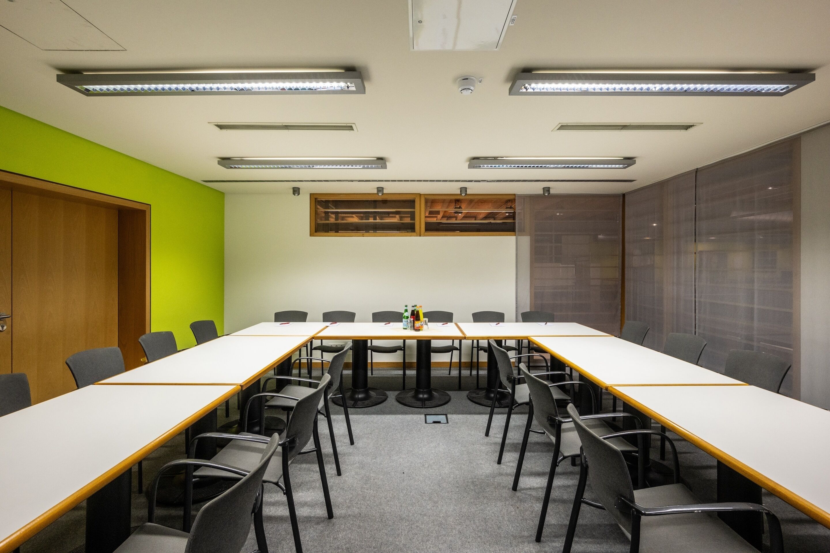 A conference room with a long table, chairs, and a bright green accent wall.