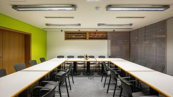 A conference room with a long table, chairs, and a bright green accent wall.