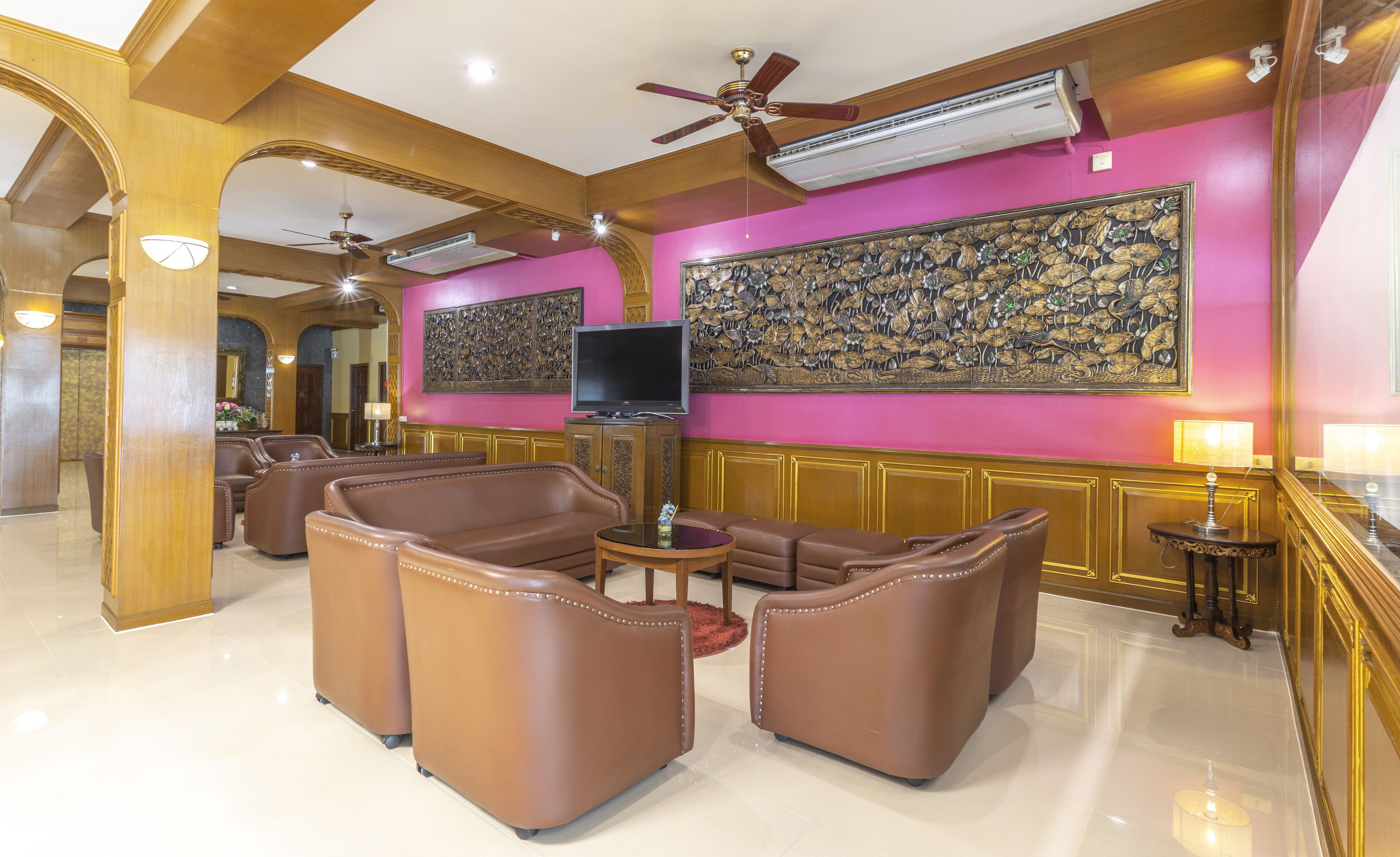A spacious lobby with leather sofas, a television, and a decorative wall.
