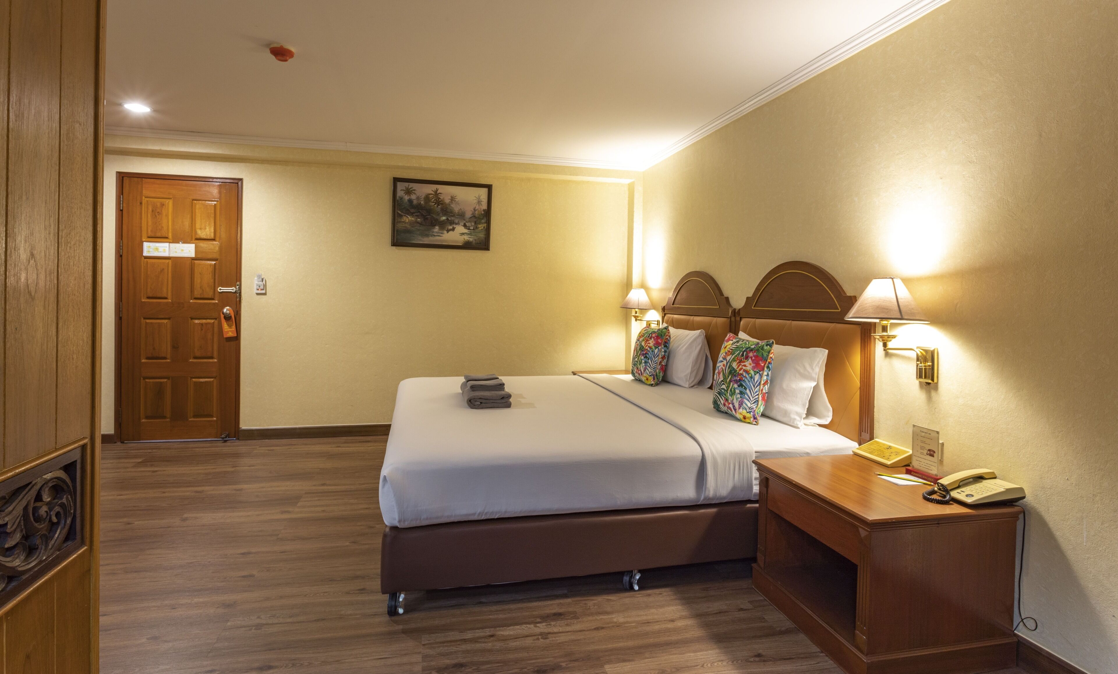A hotel room with a bed, bedside table, lamp, and a telephone.