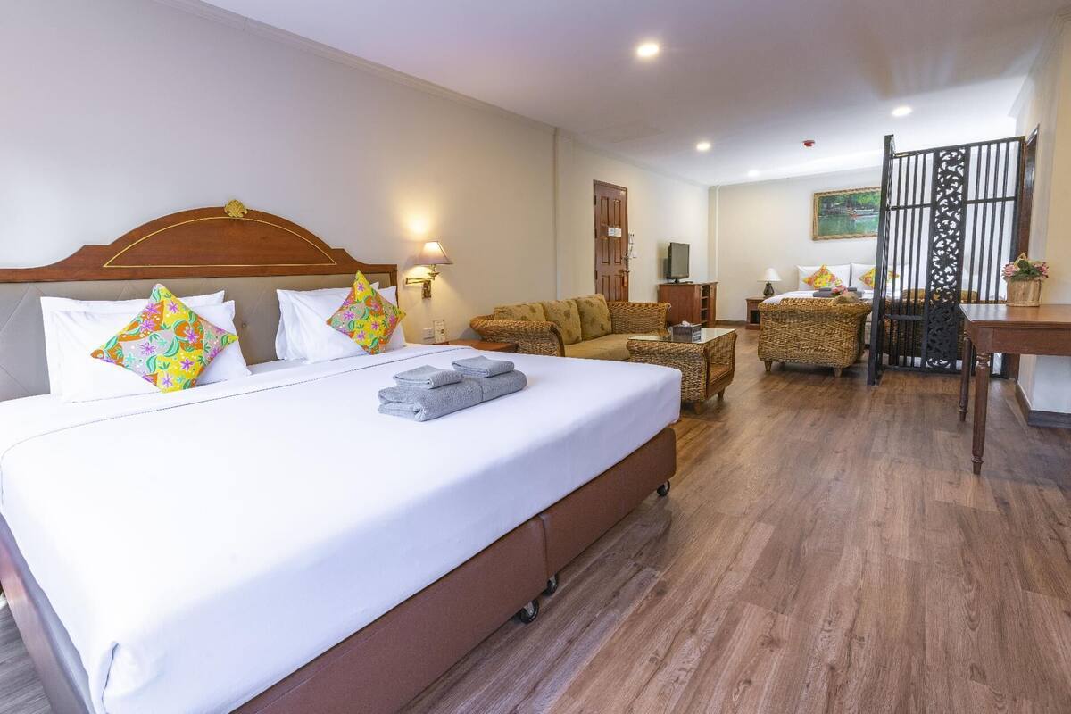 Quarto de hotel com uma cama grande, um sofá, uma mesa de jantar e uma televisão.