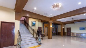 A spacious lobby with a marble staircase, wooden beams, and a chandelier. - Sabai Inn (Pattaya)