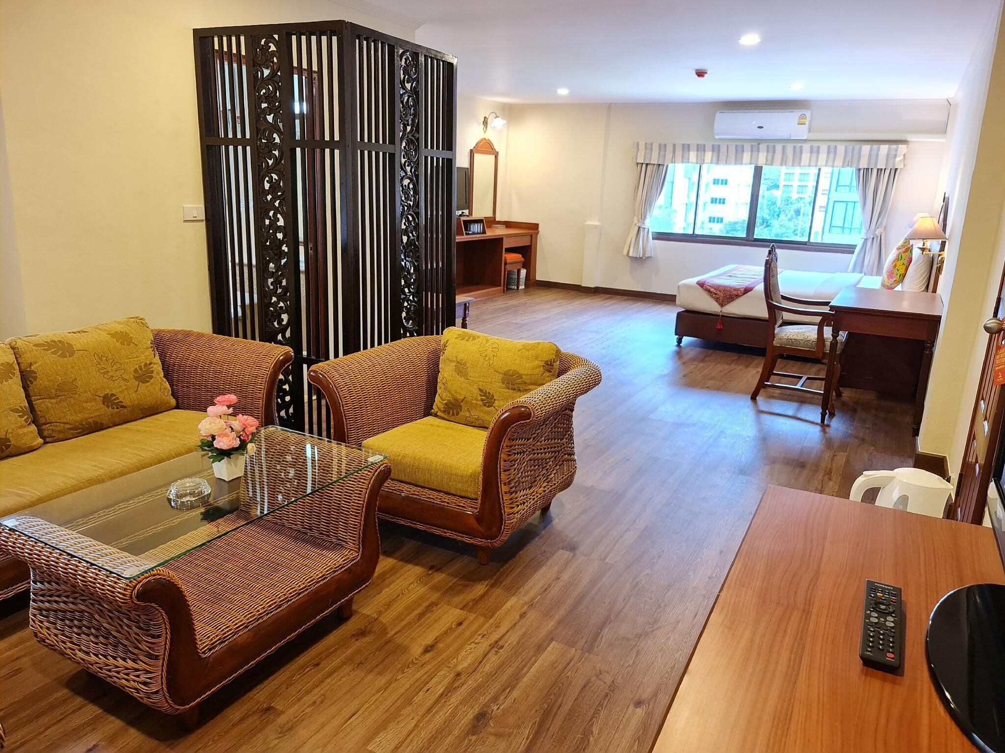 A living room with wicker furniture, a glass coffee table, and a wooden dining table.
