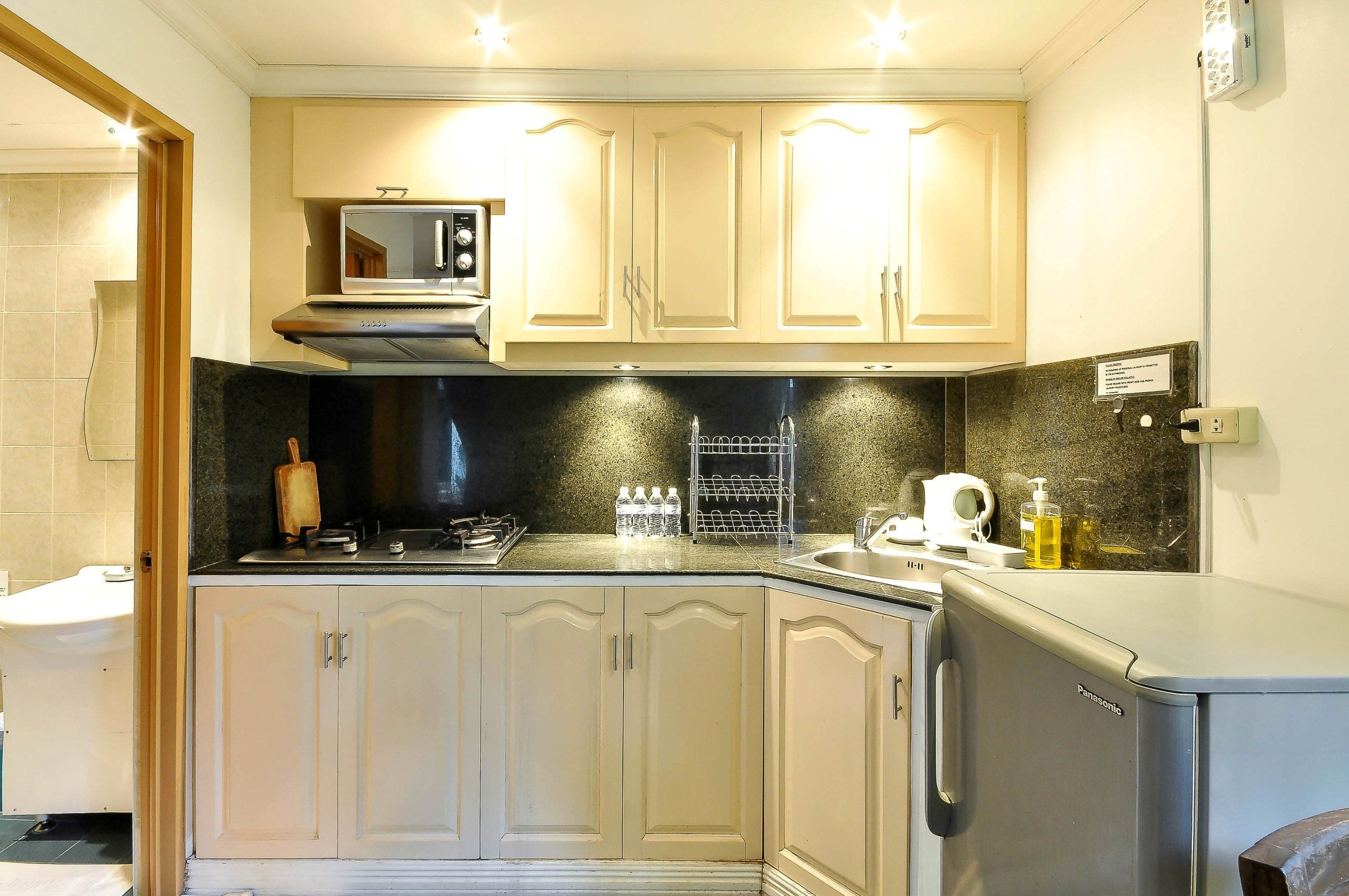 Una cocina compacta con microondas, estufa y lavabo.