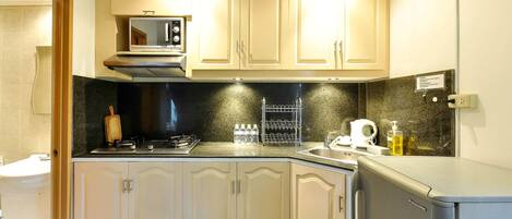 Una cocina compacta con microondas, estufa y lavabo.
