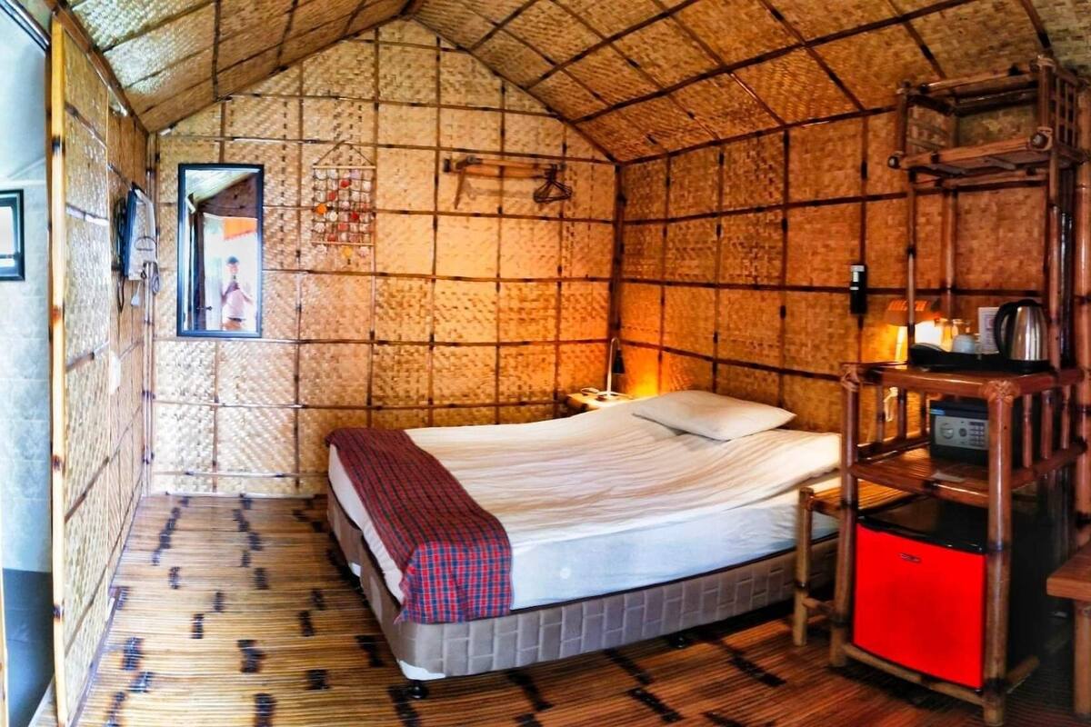 Una habitación con una cama, una mesita de noche, un armario rojo y un estante de madera.