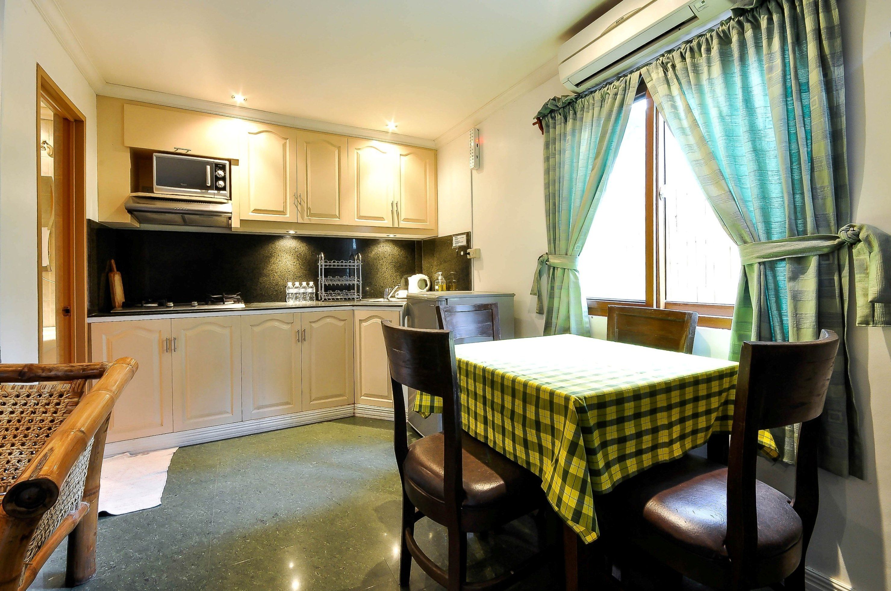 A compact kitchen with a microwave, stove, and dining area with a checkered tablecloth.