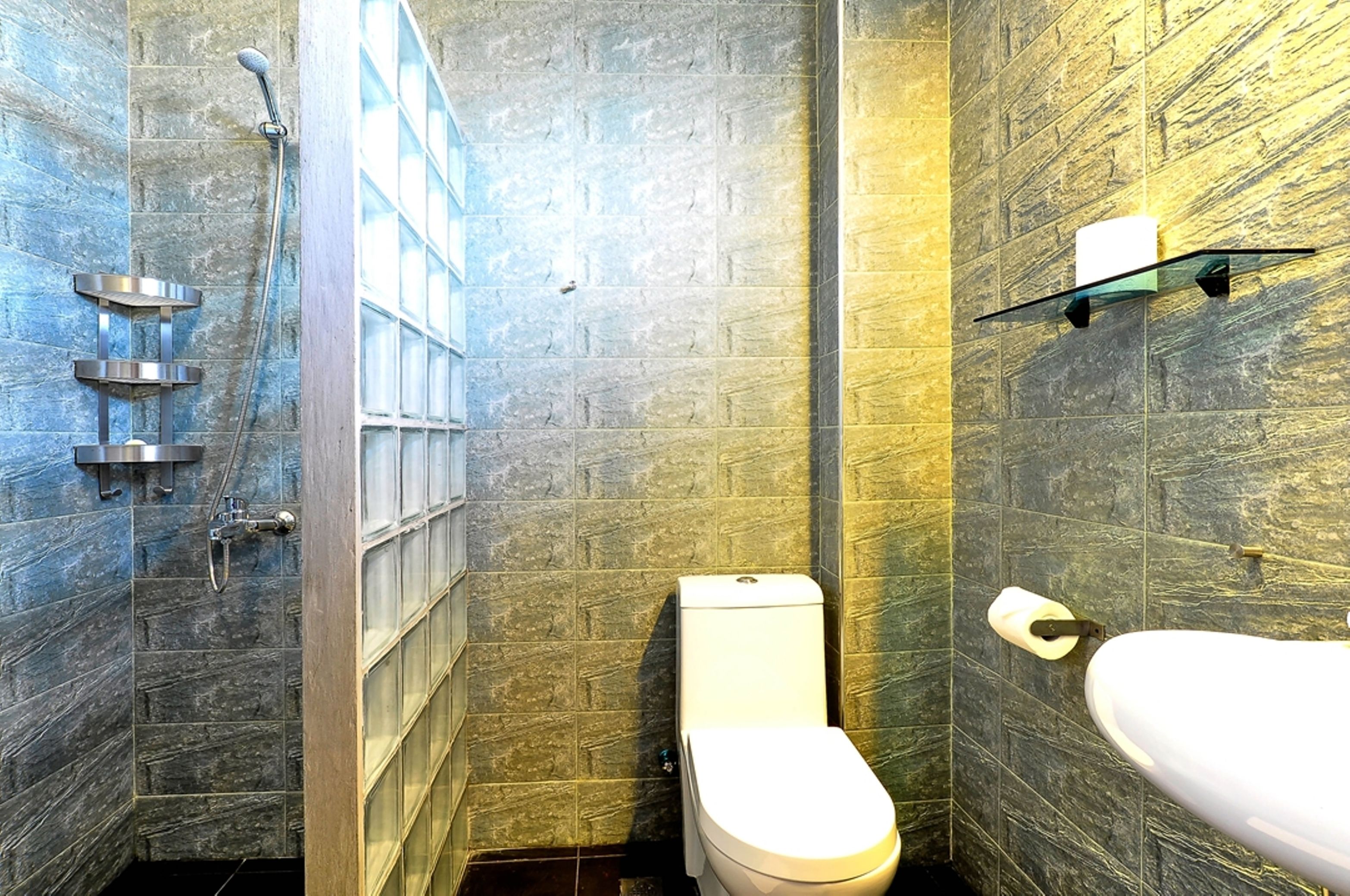 Ein modernes Badezimmer mit Duschkabine, Toilette und Waschbecken mit Ablagefläche darüber.