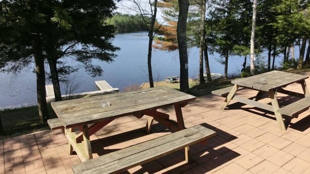 A wooden picnic table and bench set on a brick patio overlooking a lake. - H & H Restaurant and Resort (The Archipelago)