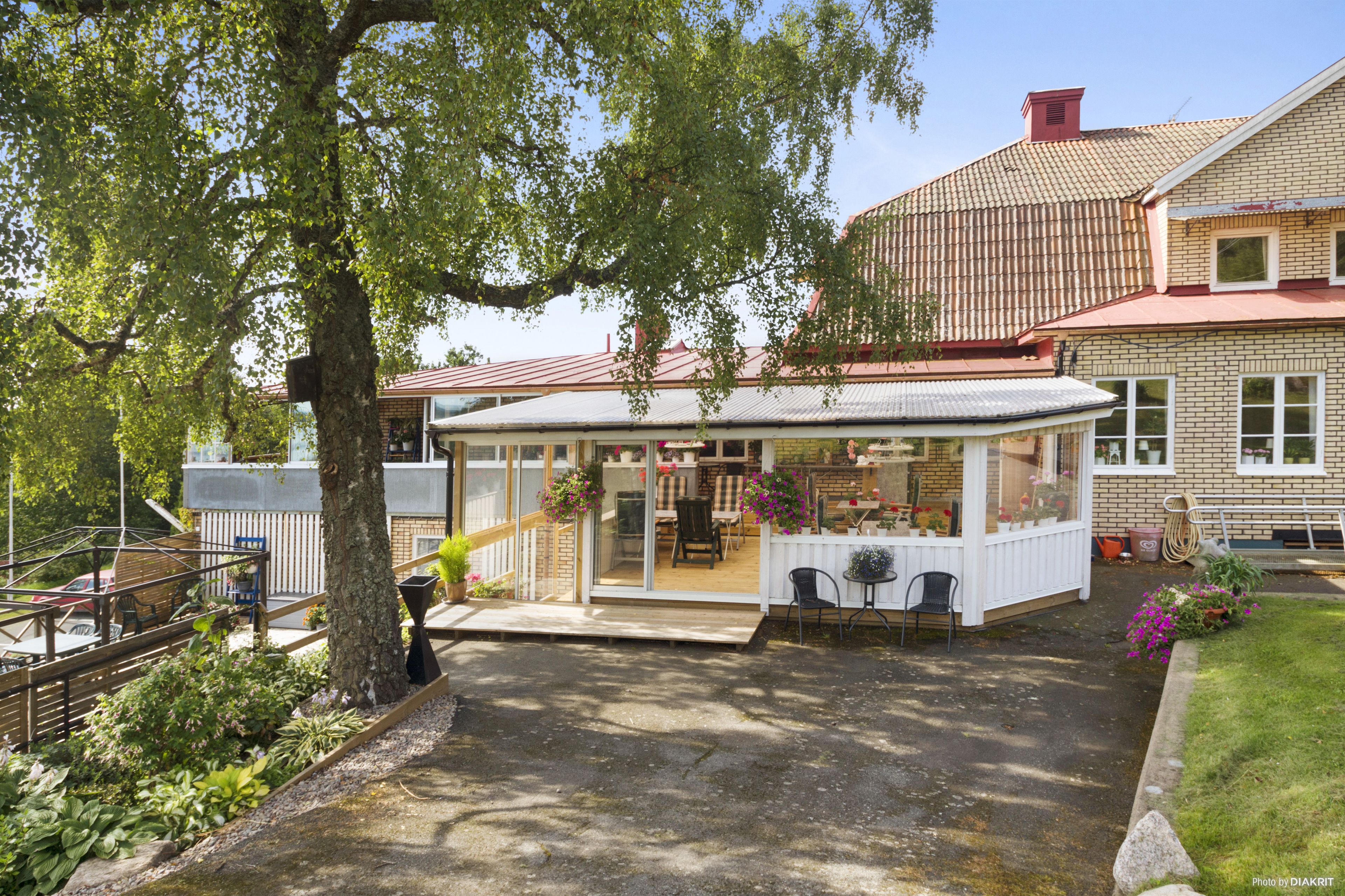 A house with a covered patio, a brick exterior, and a garden area with potted plants.