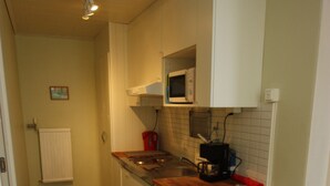 Une cuisine avec des meubles blancs, un four à micro-ondes, une machine à café et un plan de travail en bois.