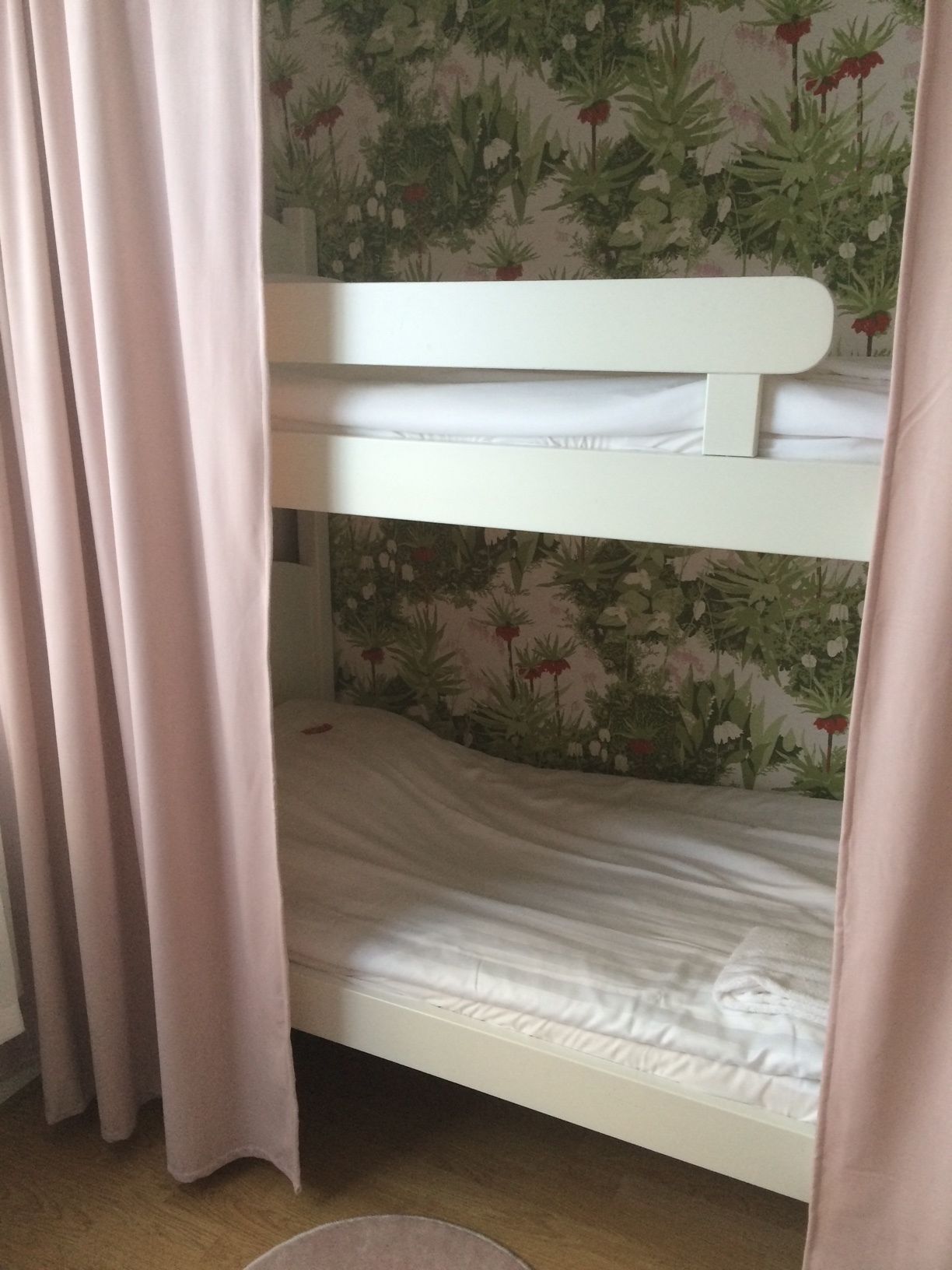 A bunk bed with a floral wallpaper background.
