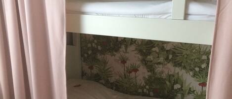 A bunk bed with a floral wallpaper background.