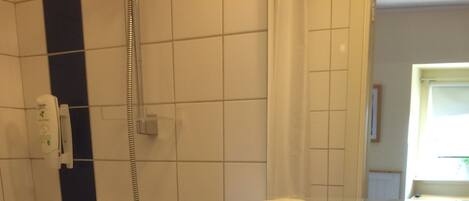 Un baño con un lavamanos blanco, un espejo y una ducha con cabezal de ducha de mano.