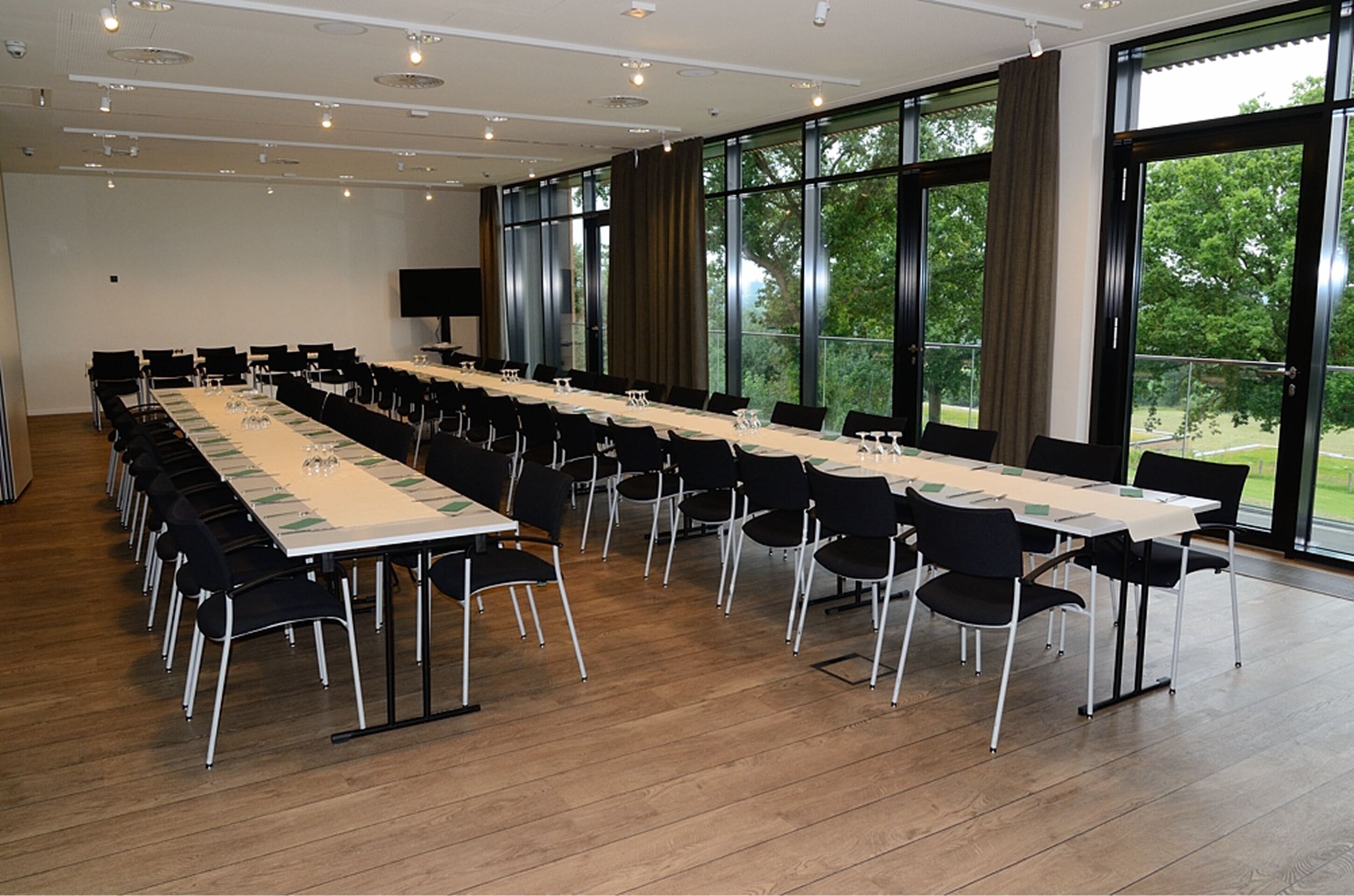 A conference room with a long table, black chairs, and large windows.